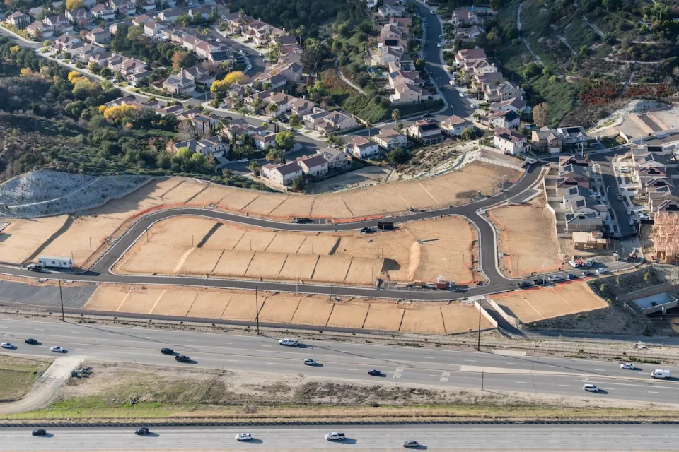 Aerial view of new neifhborhood under construction with enpty lots in foreground.